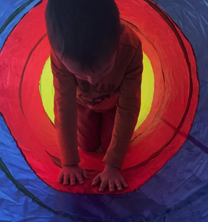 Copil care se târăște printr-un tunel colorat de joacă